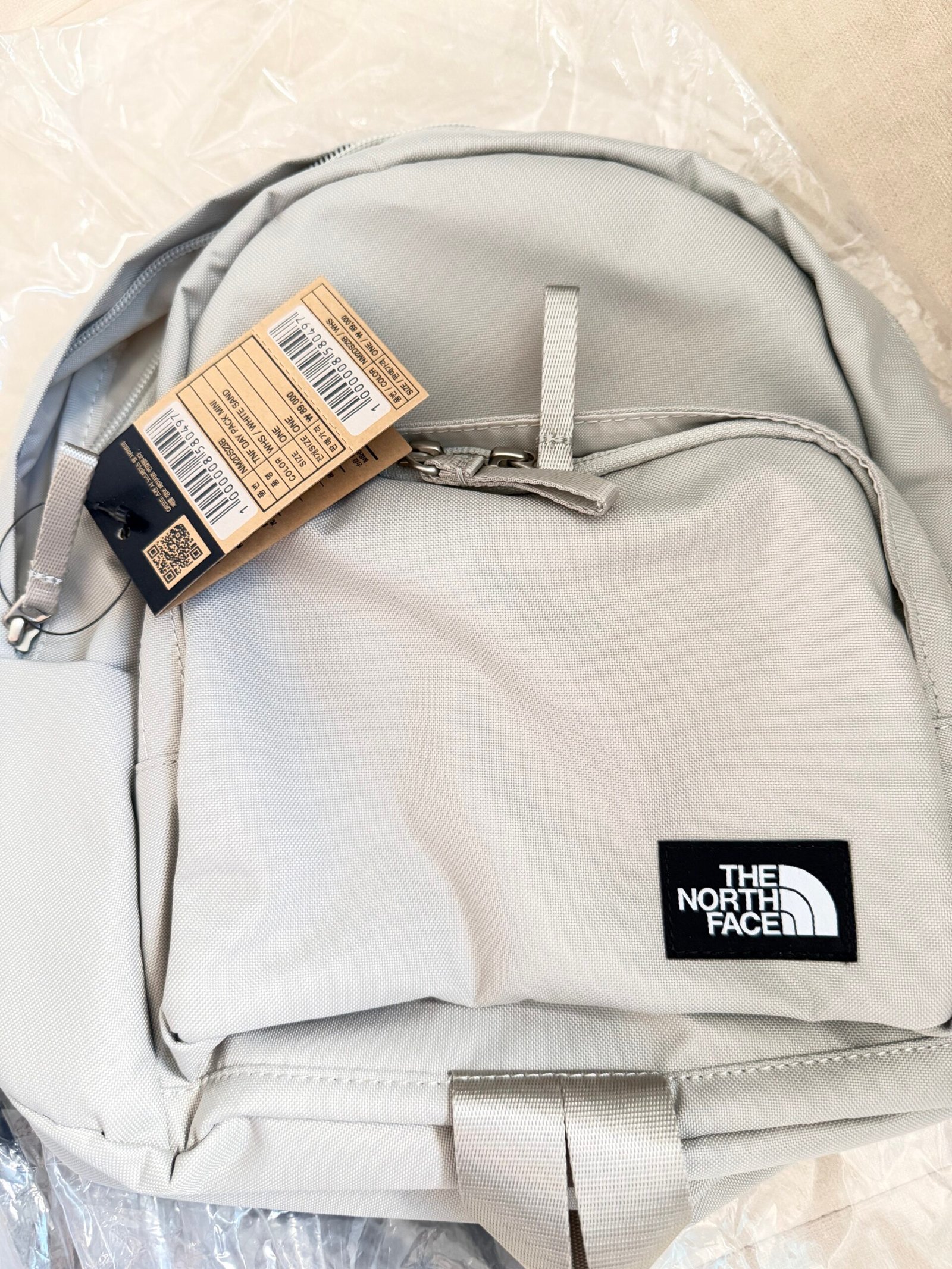 The North Face TNF Original Pack Mini in White Sand with its attached NM2DS23B hangtag
